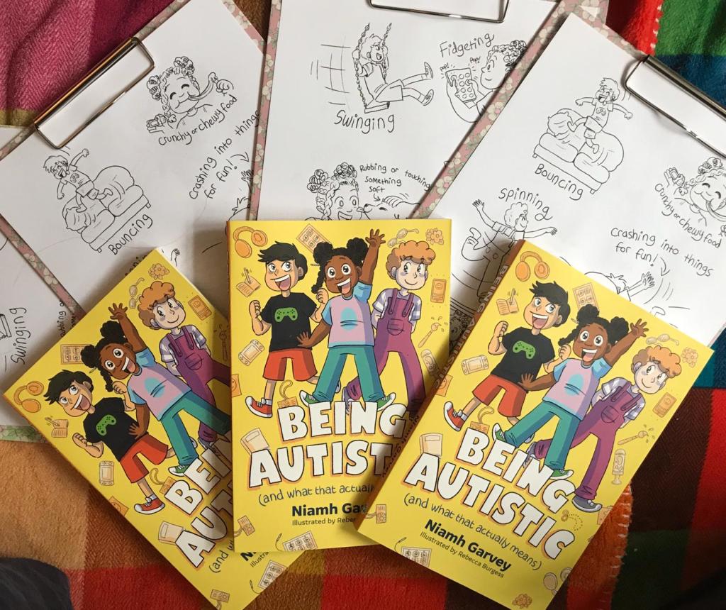 photo of 2 copies of the book over 3 clipboards with colouring sheets