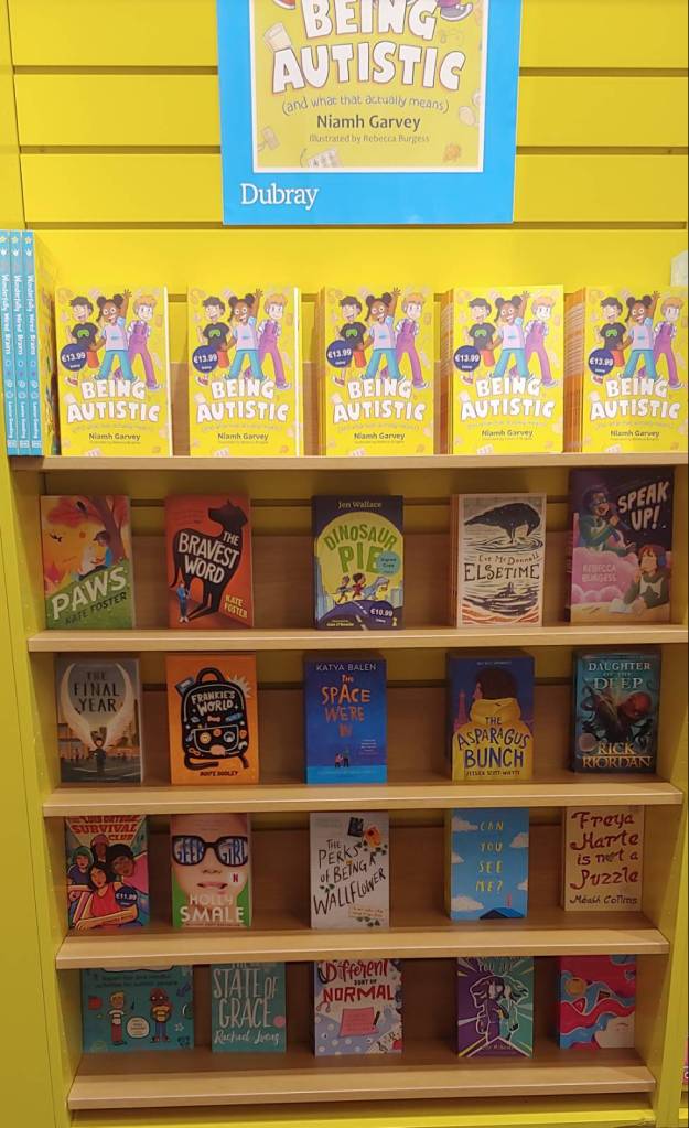 Book shelf of many kids books by neurodivergent writers or with neurodivergent characters